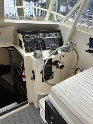 Slide: The Image of 1988 Custom Universal Ship Building Sport boat cockpit with steering wheel and control panel. - 8