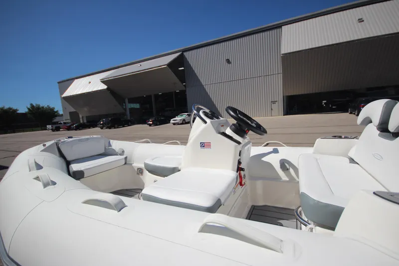 Slide: The Image of 2025 Zodiac Yachtline 400 DL NEO 50hp boat, white interior, docked near industrial building. - 1