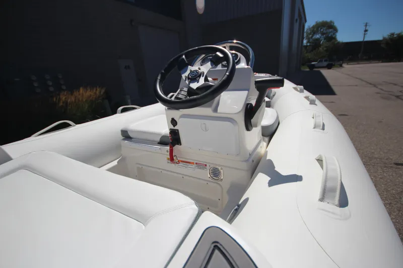 Slide: The Image of 2025 Zodiac Yachtline 400 DL NEO 50hp boat, white interior, steering console, outdoor setting. - 10