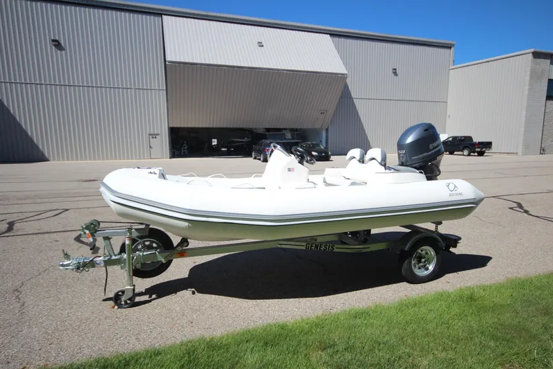 Slide: The Image of 2025 Zodiac Yachtline 400 DL NEO 50hp boat on trailer, parked outside industrial building. - 5