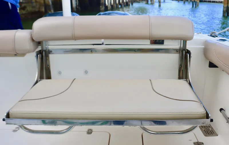 Slide: The Image of 2017 Pursuit DC 295 Dual Console boat seat with beige upholstery and stainless steel frame. - 17