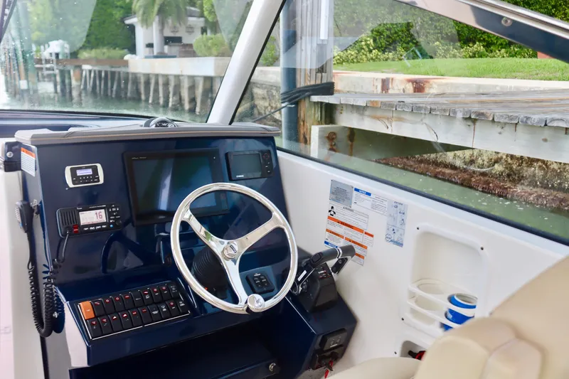 Slide: The Image of 2017 Pursuit DC 295 Dual Console boat helm with steering wheel and navigation equipment. - 2