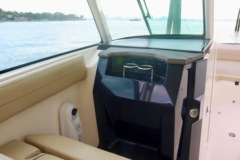 Slide: The Image of 2017 Pursuit DC 295 Dual Console interior with seating and storage, overlooking water. - 7