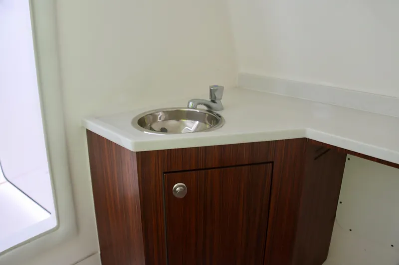 Slide: The Image of 2017 Pursuit DC 295 Dual Console boat interior with wooden cabinet and sink. - 8