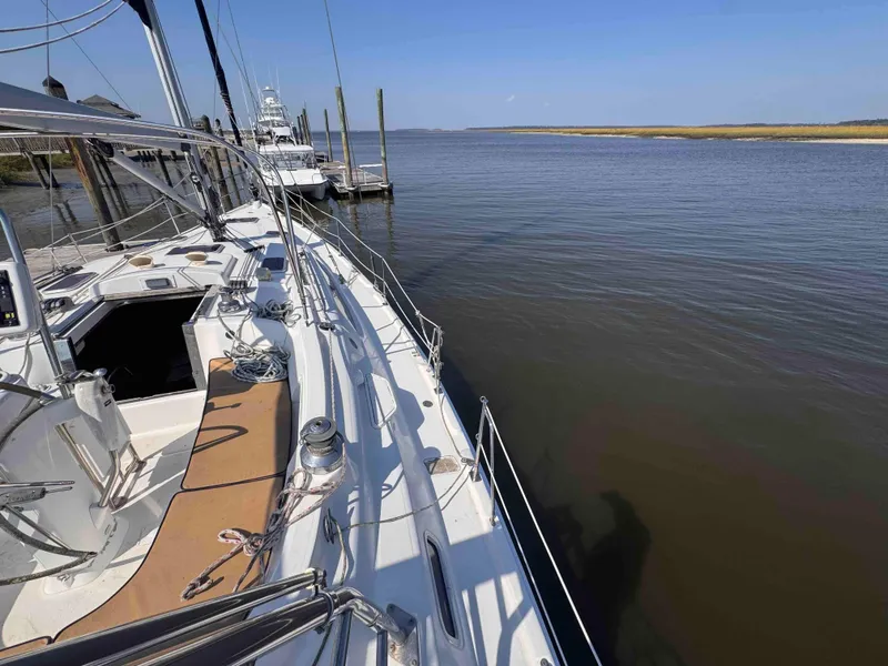 Slide: The Image of 2008 Hunter 45 Center Cockpit sailboat docked by calm waters under clear blue sky. - 17