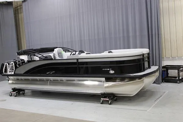 Slide: The Image of 2025 Harris 230 CRUISER pontoon boat in showroom, sleek black and white design. - 1