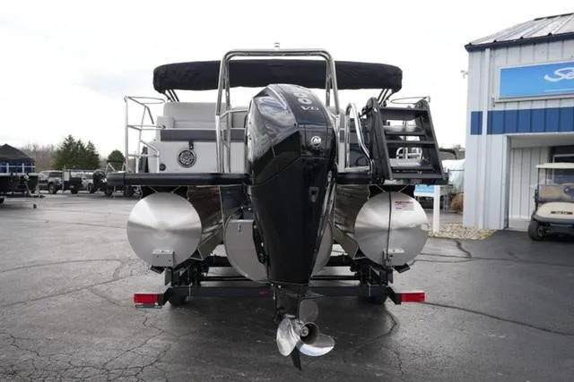 Slide: The Image of 2025 Harris 230 Cruiser pontoon boat with powerful outboard motor, parked on a trailer. - 7