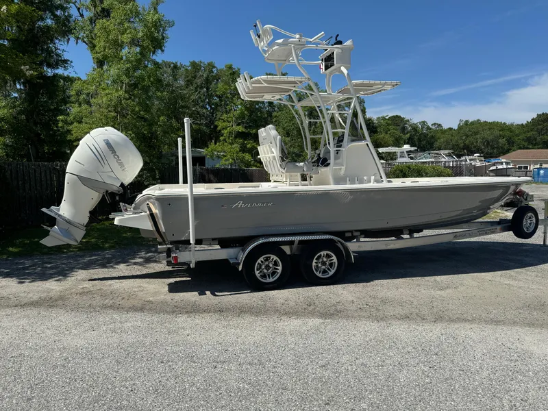 Slide: The Image of 2024 Avenger AV26 boat on trailer with outboard motor, parked outdoors. - 3