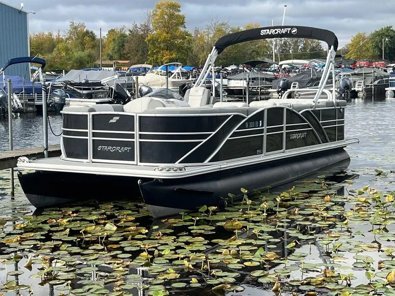 Slide: The Image of 2018 Starcraft 23 C pontoon boat docked on a lake with lily pads. - 3