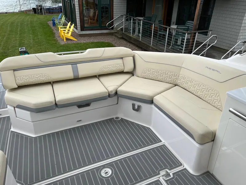 Slide: The Image of 2022 Regal LS36 boat with beige seating and gray flooring, docked near a lawn. - 30