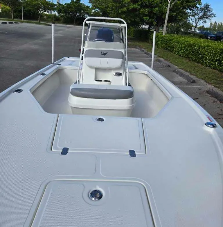 Slide: The Image of 2025 Mako 18 LTS boat, white deck, parked outdoors, surrounded by greenery. - 4