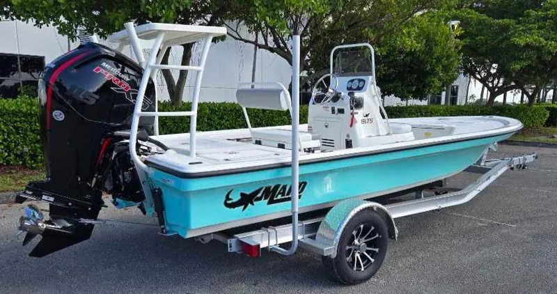 Slide: The Image of 2025 Mako 18 LTS boat on trailer, turquoise hull, outboard motor, parked outdoors. - 6