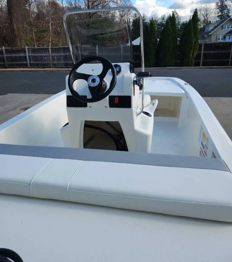 Slide: The Image of 2025 Mako Pro Skiff 13 CC boat with steering console, parked outdoors. - 3
