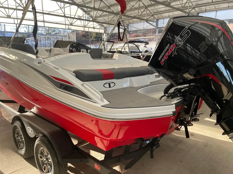 Slide: The Image of 2025 Tahoe T21 boat with red and white design, on trailer, under a canopy. - 2