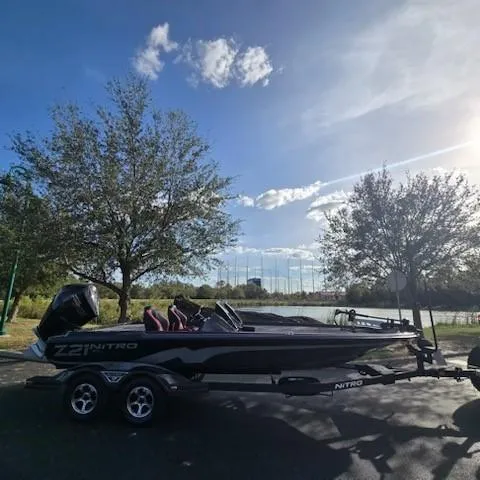 Slide: The Image of 2025 Nitro Z21 XL boat on trailer, parked near trees and water under a blue sky. - 4