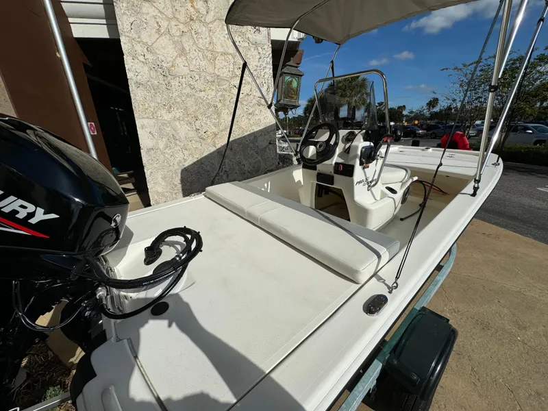 Slide: The Image of 2025 Mako Pro Skiff 13 CC boat with Mercury engine, parked outdoors. - 2