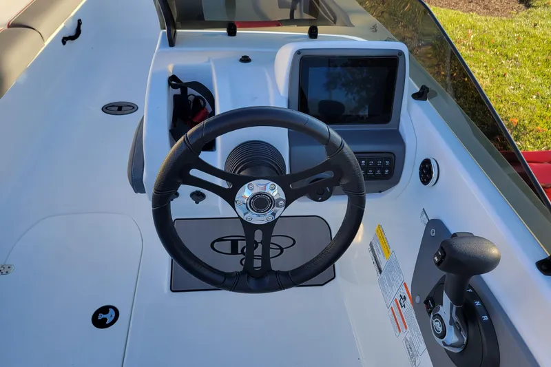 Slide: The Image of 2025 Tahoe T21 boat dashboard with steering wheel, control panel, and throttle lever. - 74