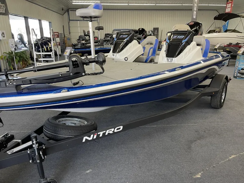 Slide: The Image of 2025 Nitro Z18 boat in showroom, blue and white design, on trailer. - 2