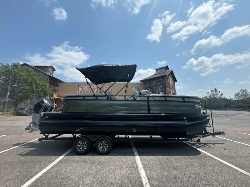 Slide: The Image of 2025 Regency 230 DL3 pontoon boat parked in a sunny lot. - 2