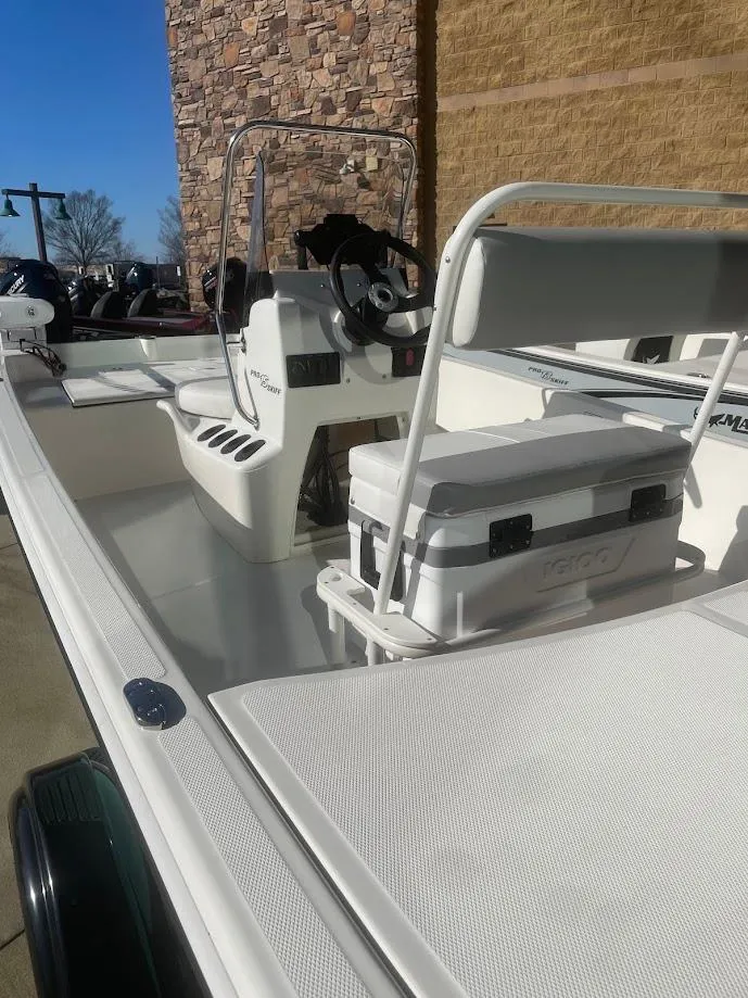 Slide: The Image of 2025 Mako Pro Skiff 15 CC boat with seating and steering console, parked outdoors. - 1