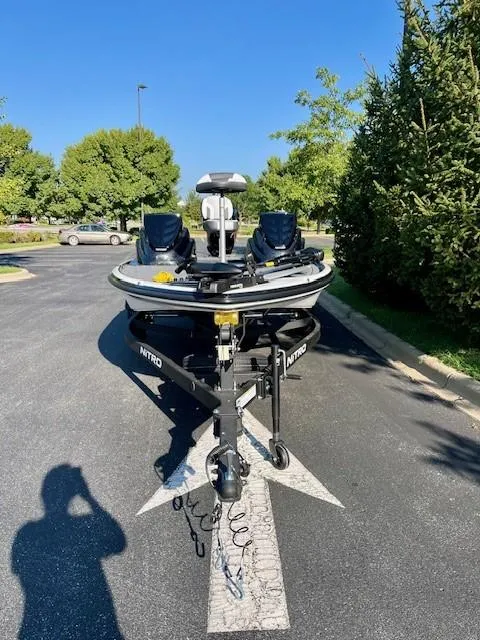 Slide: The Image of 2025 Nitro Z17 boat parked on asphalt, surrounded by trees under clear blue sky. - 2