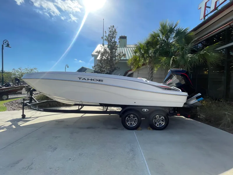The Image of 2025 Tahoe T21 boat on trailer under sunny sky, parked near palm trees. - 0
