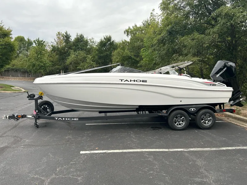 The Image of 2025 Tahoe T21 boat on trailer, parked outdoors, surrounded by trees. - 0