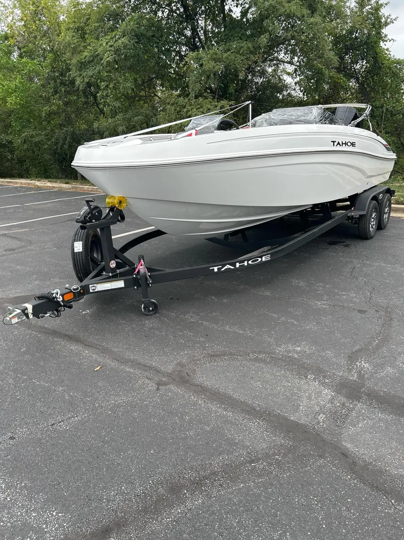 Slide: The Image of 2025 Tahoe T21 boat on trailer in parking lot, surrounded by trees. - 2