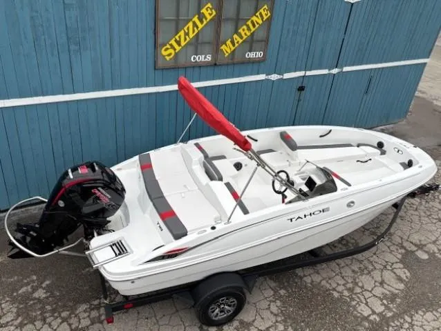 Slide: The Image of 2025 Tahoe T18 boat with red canopy on trailer, parked by blue building. - 4