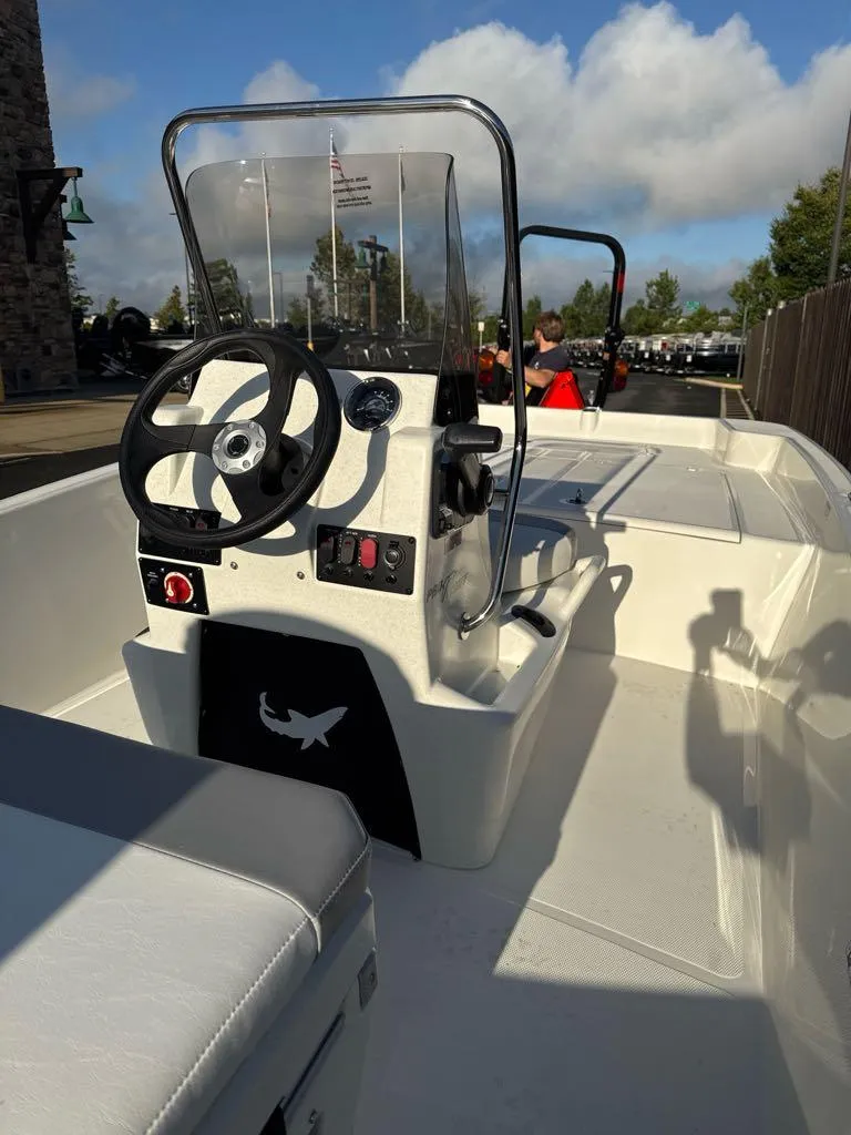 Slide: The Image of 2025 Mako Pro Skiff 17 CC boat with center console and steering wheel, docked outdoors. - 1