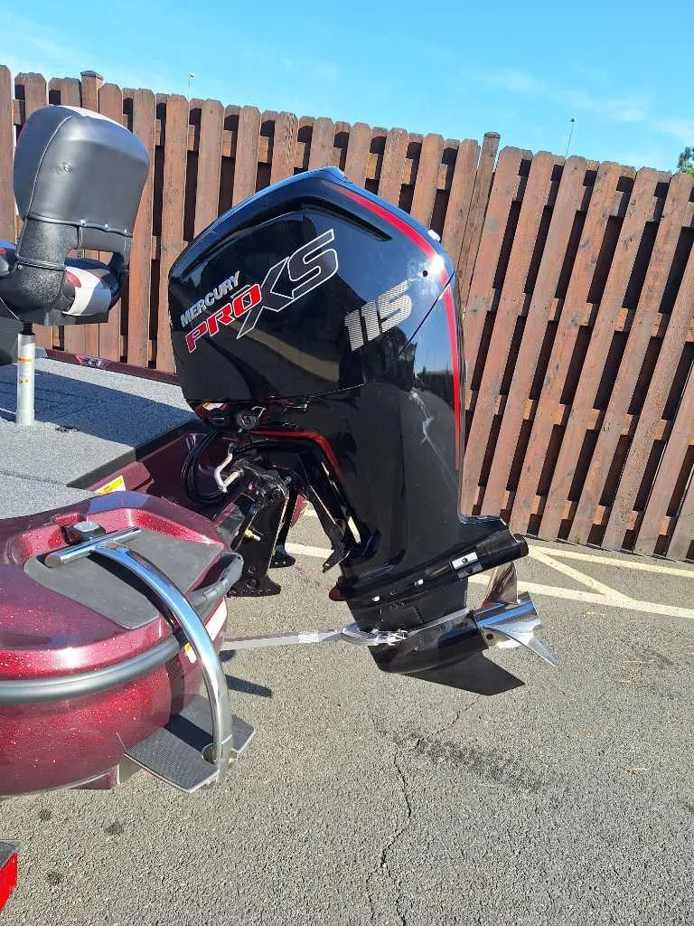 Slide: The Image of 2025 Nitro Z17 boat with Mercury Pro XS 115 outboard motor, parked near wooden fence. - 2