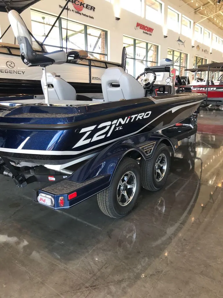 Slide: The Image of 2025 Nitro Z21 XL boat in showroom, sleek design, dual seats, and trailer. - 5