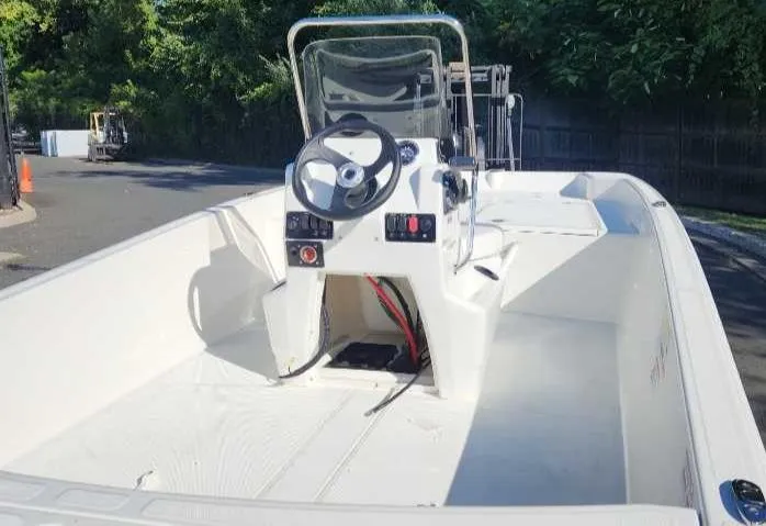 Slide: The Image of 2025 Mako Pro Skiff 17 CC boat, center console, white interior, parked outdoors. - 2