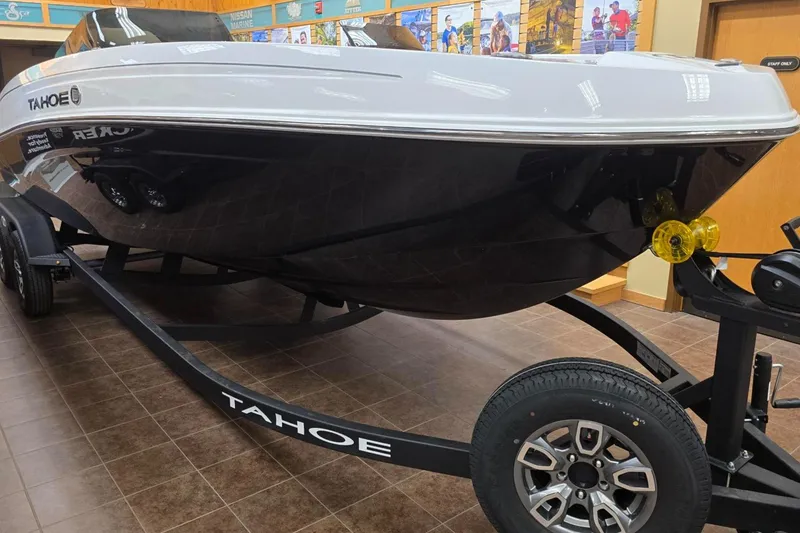 Slide: The Image of 2025 Tahoe T21 boat on display with trailer in showroom. - 1