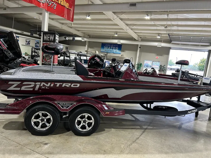 Slide: The Image of 2025 Nitro Z21 XL boat in showroom, maroon color, on a trailer. - 2