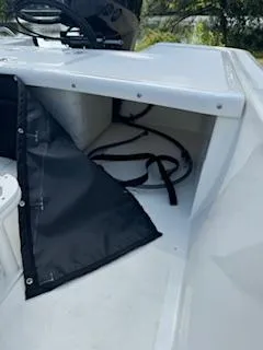 Slide: The Image of 2025 Mako Pro Skiff 17 CC storage compartment with black cover and visible cables. - 45