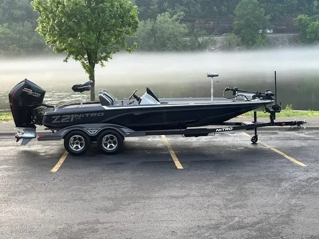 The Image of 2025 Nitro Z21 XL boat with powerful engine, parked in a lot, surrounded by greenery. - 0