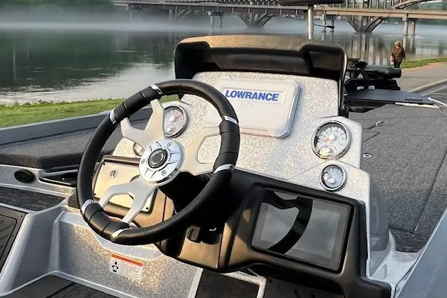 Slide: The Image of 2025 Nitro Z21 XL boat dashboard with steering wheel and Lowrance electronics by a serene river. - 112
