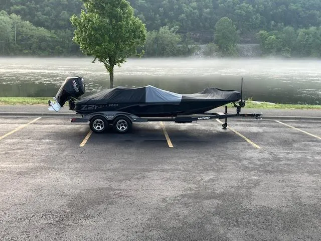 Slide: The Image of 2025 Nitro Z21 XL boat parked by a misty lake, showcasing sleek design and modern features. - 2