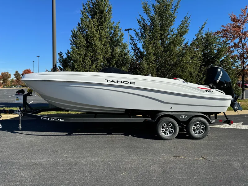 Slide: The Image of 2025 Tahoe T21 boat on trailer, parked outdoors, surrounded by trees. - 1