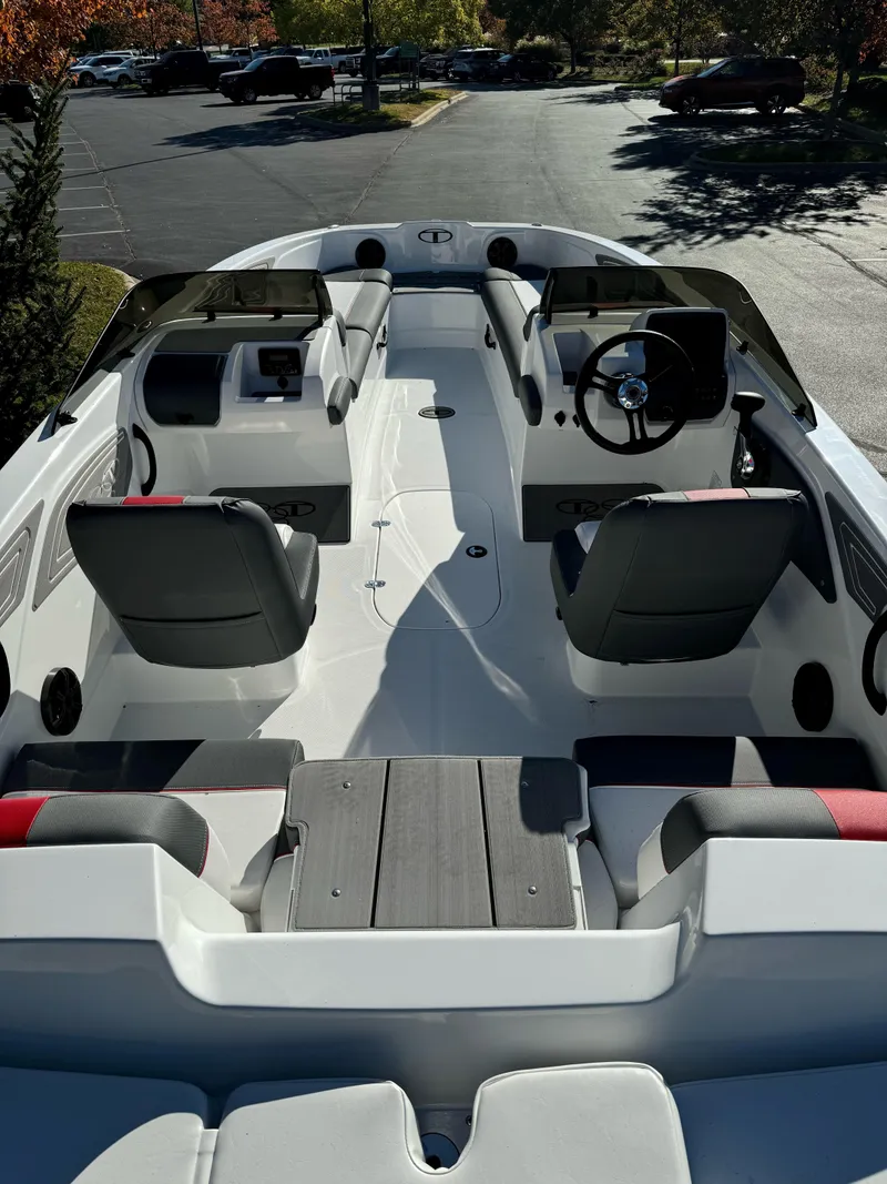 Slide: The Image of 2025 Tahoe T21 boat interior with seating and steering wheel, parked outdoors. - 2