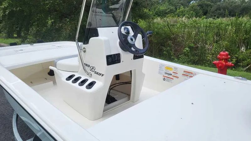 Slide: The Image of 2025 Mako Pro Skiff 13 CC boat with steering console, outdoors near greenery. - 3