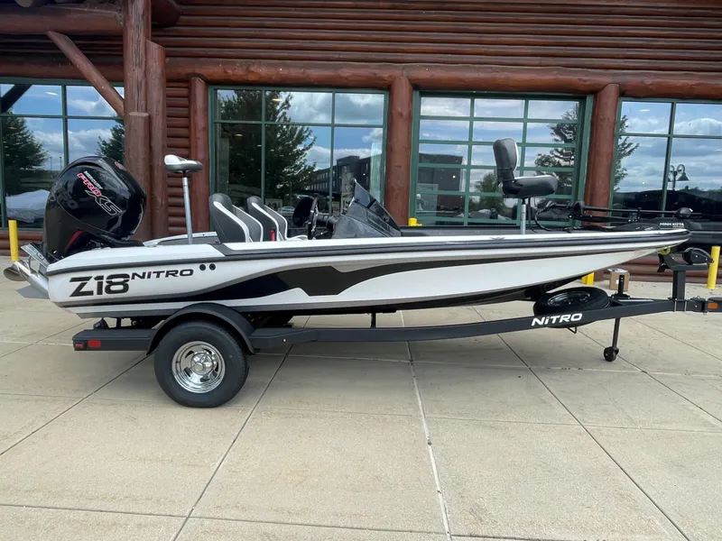 The Image of 2025 Nitro Z18 boat on trailer, parked outside a log building. - 0