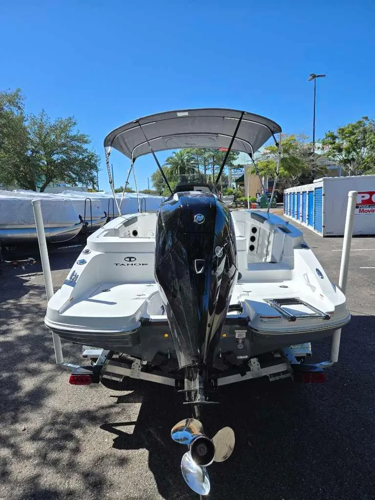 Slide: The Image of 2025 Tahoe 2150 CC boat with outboard motor, parked outdoors under clear blue sky. - 3