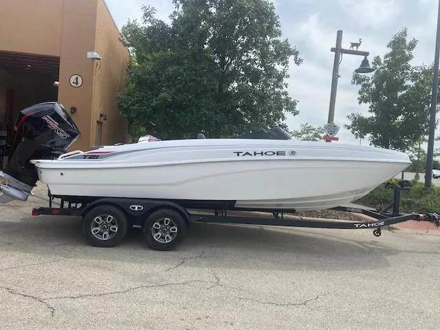 The Image of 2025 Tahoe T21 boat on trailer, parked outdoors near trees and building. - 0
