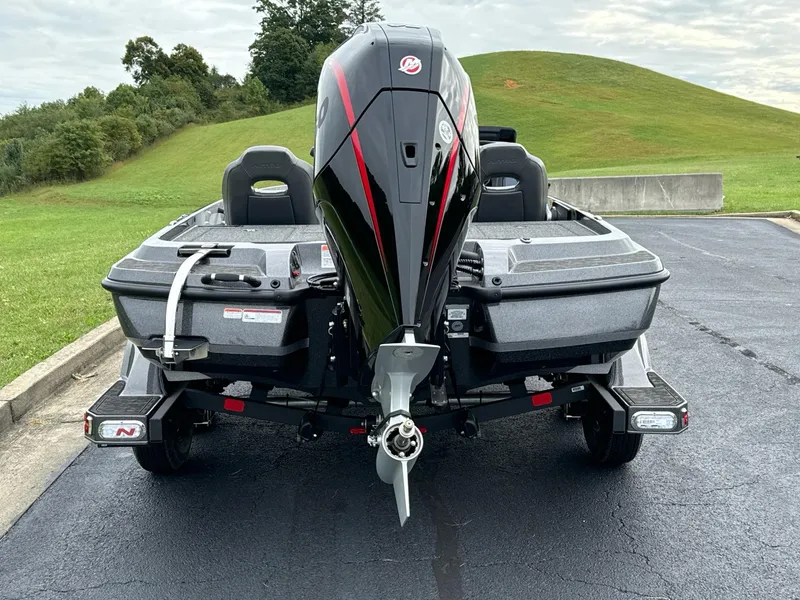 Slide: The Image of 2025 Nitro Z21 XL boat, rear view, parked on asphalt near grassy hill. - 11