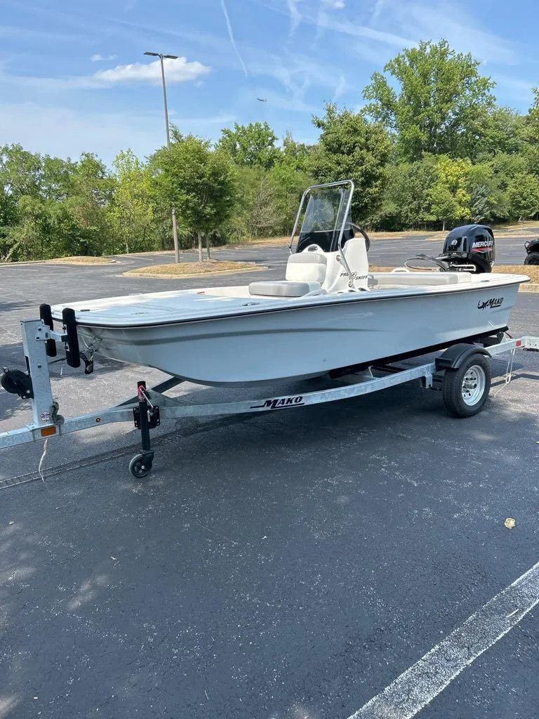 Slide: The Image of 2025 Mako Pro Skiff 13 CC on trailer in parking lot, clear sky background. - 2