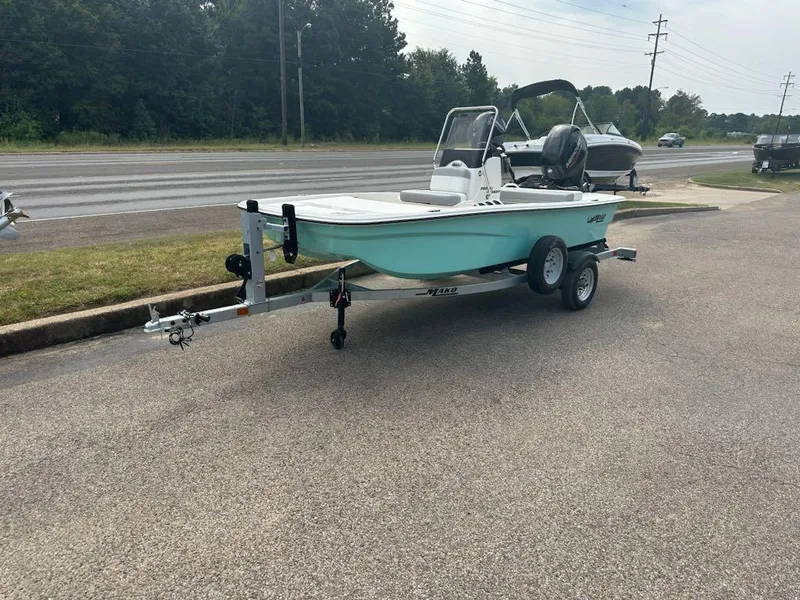Slide: The Image of 2025 Mako Pro Skiff 13 CC boat on trailer, parked near a road. - 1
