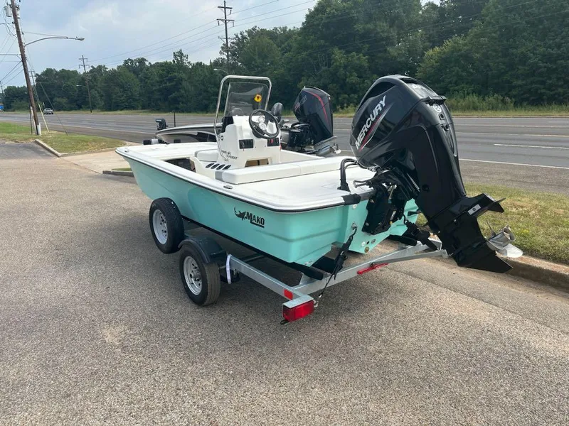 Slide: The Image of 2025 Mako Pro Skiff 13 CC boat on trailer, parked near a road. - 2