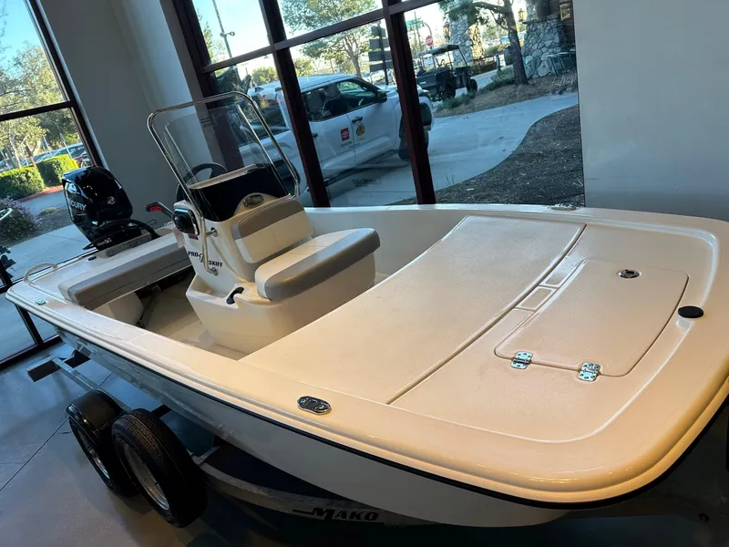 Slide: The Image of 2025 Mako Pro Skiff 13 CC boat displayed indoors, featuring a sleek design and modern console. - 2